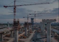 Obra de viaduto com gruas e pilares de concreto
