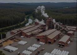 Vista aérea de fábrica de papel e celulose cercada por floresta